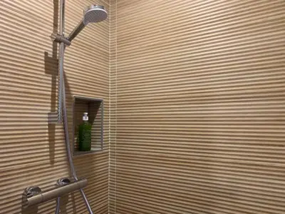 a shower with a shower head and a bottle on a shelf at La Parenthese Saint Donat in Aix-en-Provence