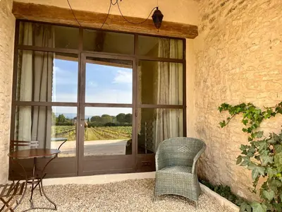 a patio with a glass door with a table and a chair at La Verrière à Bonnieux in Bonnieux