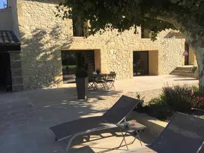a patio with two chairs and a table in front of a building at MAS DE CHARME EN PROVENCE in Le Thor