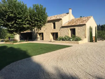 a stone house with a tree and a driveway at MAS DE CHARME EN PROVENCE in Le Thor