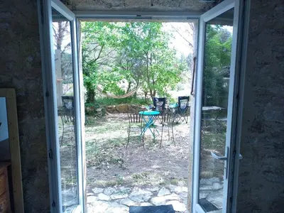 an open door to a patio with a table and chairs at Sous un chêne bicentenaire in Lambesc