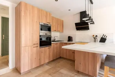 a kitchen with wooden cabinets and a white counter top at Le marronnier 3: Superbe appart au coeur de la petite venise in LʼIsle-sur-la-Sorgue