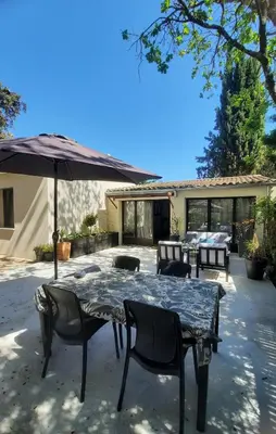 a patio with a table and chairs and an umbrella at Gîte des Bartavelles in Saint-Didier