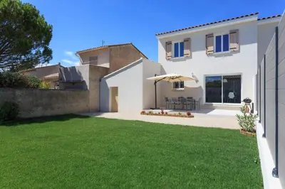 a white house with an umbrella and a lawn at Villa Lisa - piscine chauffée in LʼIsle-sur-la-Sorgue