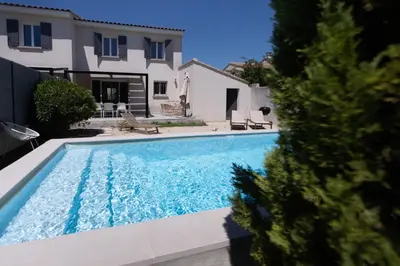 a backyard with a swimming pool and a chair at Villa Anna - piscine privée proche du centre historique in LʼIsle-sur-la-Sorgue