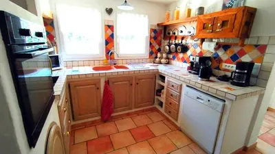 a kitchen with wooden cabinets and a tile floor at Villa Chênaie in Bédoin
