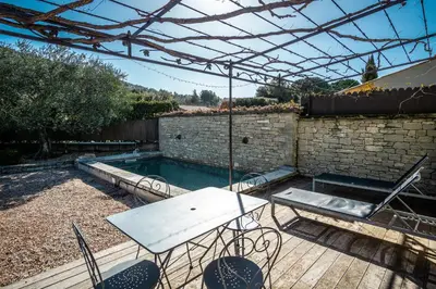 a patio with a table and chairs and a pool at Gîte tout confort - jardin et piscine in Lagnes