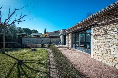 a stone house with a window and a yard at Gîte tout confort - jardin et piscine in Lagnes