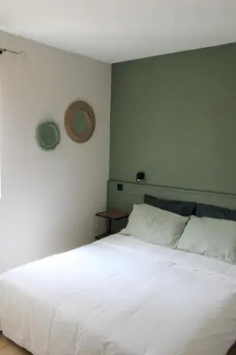 a bedroom with a white bed with a green wall at Bastidon avec piscine Gordes Lubéron in Gordes