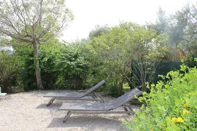 two chaise lounges in a garden with trees and bushes at Bastidon avec piscine Gordes Lubéron in Gordes