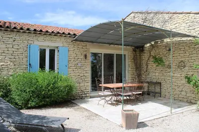 a patio with a table and chairs under an umbrella at Bastidon avec piscine Gordes Lubéron in Gordes