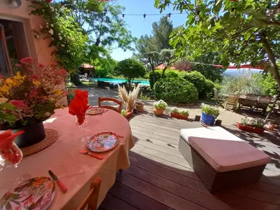 a wooden deck with a table and chairs on it at Le jardin de Sabine in Éguilles