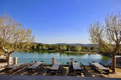 a row of lounge chairs in front of a lake at Apartement Beata in Provence, Golf Pont Royal in Mallemort