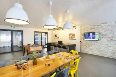 a dining room with a table and a tv on a brick wall at Résidence Nemea Aix Campus 2 in Aix-en-Provence