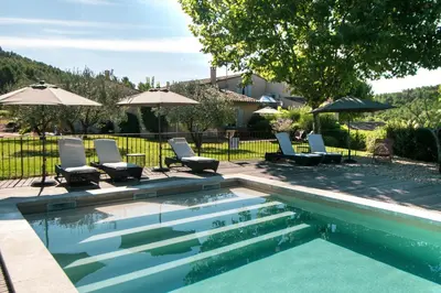 a swimming pool with chairs and umbrellas at Domaine Perréal Les Gîtes in Gargas