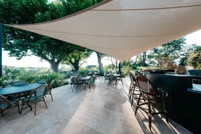 a patio with tables and chairs and an umbrella at Domaine Perréal Les Gîtes in Gargas