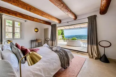 a bedroom with a large bed and a large window at Le Mas Victoria in Gordes