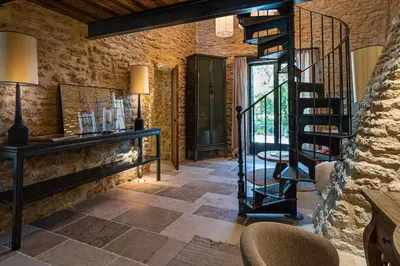 a room with a stone wall and a spiral staircase at Le Mas Luca in Gordes