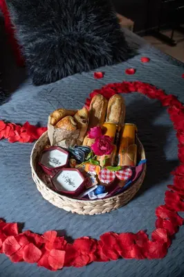 a basket filled with bread and flowers on a bed at Eden House, Cocon sensuel et romantique avec jacuzzi in Carpentras