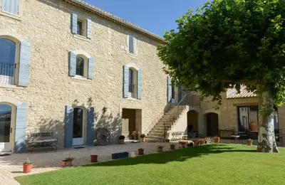 a large stone building with a tree in front of it at La Bastide Neuve in Joucas