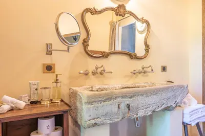 a bathroom with a stone sink and a mirror at Prieuré Notre-Dame de Conil - 12e siècle in Rognes