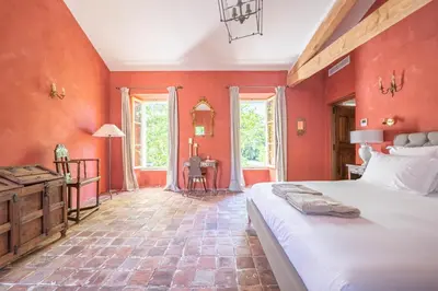a bedroom with red walls and a bed and a desk at Prieuré Notre-Dame de Conil - 12e siècle in Rognes