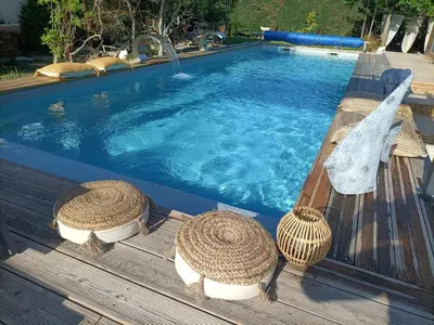 a swimming pool with two straw hats on a wooden deck at Cocoon inn&Spa in Saint-Saturnin-les-Avignon
