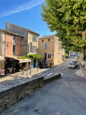 a street in a town with buildings and a tree at La Maison d’Helene & Antoine à Bonnieux XII siècle in Bonnieux
