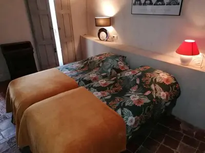 a bedroom with a bed and a table with a lamp at La Maison d’Helene & Antoine à Bonnieux XII siècle in Bonnieux