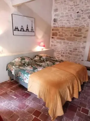 a bedroom with a bed and a brick wall at La Maison d’Helene & Antoine à Bonnieux XII siècle in Bonnieux