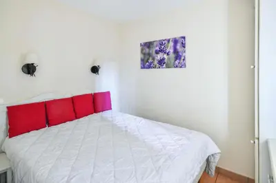 a bedroom with a white bed with red pillows at Village Pont Royal en Provence - maeva Home - Appartement 2 pièces 6 personnes Sélection MAE-7984 in Mallemort