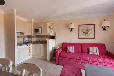 a living room with a red couch and a kitchen at Les Coteaux de Pont Royal en Provence - maeva Home - Maison 3 Pièces 6 Personnes - Sélection MAE-7944 in Mallemort