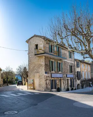 an old stone building with a balcony on a street at La Terrasse d'Eygalières in Eygalières