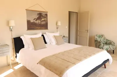 a bedroom with a large white bed and a chair at Le Mas Joséphine in Saint-Rémy-de-Provence