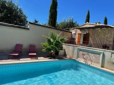 a swimming pool with two purple chairs next to a house at Les Célestins - Studios indépendants in Carpentras