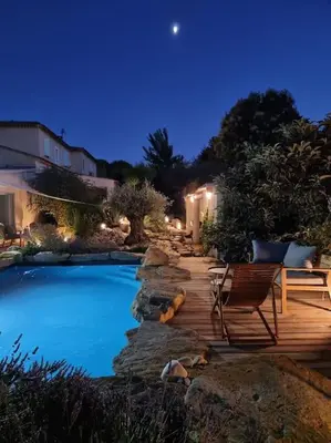 a swimming pool with a wooden deck and a chair at Une Oasis au Pays de Cézanne in Aix-en-Provence