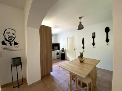 a dining room with a wooden table and a kitchen at Une Oasis au Pays de Cézanne in Aix-en-Provence