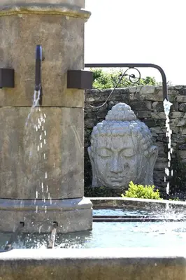 a water fountain with a statue of a head at La Borie Oubliée in Gordes