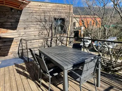 a wooden deck with a table and two chairs at campdebaseventoux, vue sur le ventoux insolite in Bédoin
