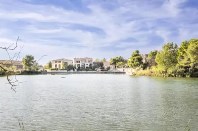 a view of a lake with houses in the background at Les Maisons de Pont Royal en Provence - maeva Home - Maison 3 pièces 6 personnes climatisé - Sélection MAE-6421 in Mallemort