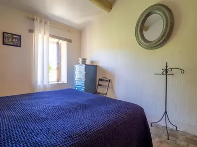 a bedroom with a blue bed and a mirror at Le Mas Réséda in Goult