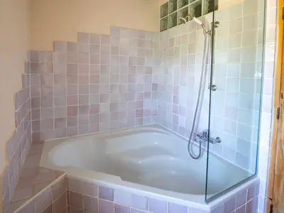 a bath tub in a bathroom with blue tiles at Le Mas Réséda in Goult