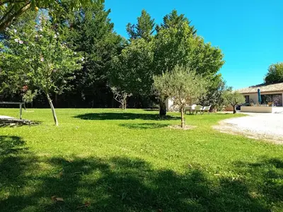 a field of grass with trees and a building at Le Mas Paolo in Le Thor