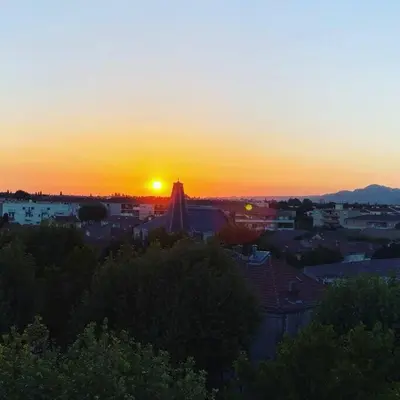 a sunset over a city with the sun setting at La Suite TAMAN au centre de Salon in Salon-de-Provence