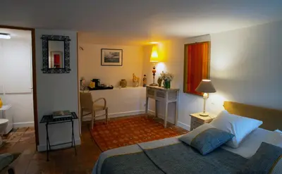 a bedroom with a bed and a desk with a sink at Le Clos des Amandiers in Simiane-la-Rotonde