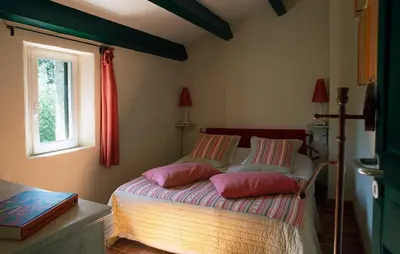 a bedroom with a bed with pink pillows on it at Le Clos des Amandiers in Simiane-la-Rotonde