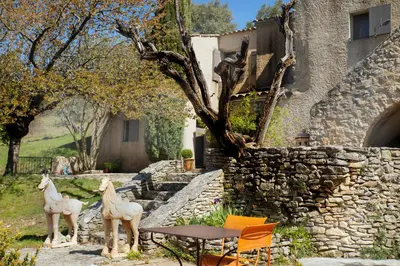 two statues of horses standing next to a stone wall at Le Clos des Amandiers in Simiane-la-Rotonde