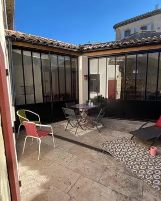 a patio with chairs and a table and windows at Les Remparts de Lauris Coeur Médiéval et Patio in Lauris