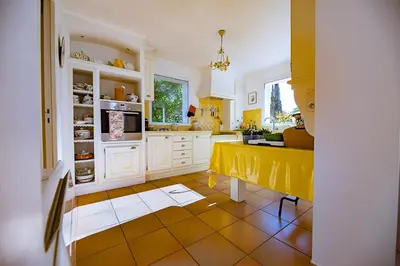 a kitchen with white cabinets and a yellow tile floor at Maison des lavandes in Saint-Cannat