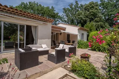 a patio with wicker furniture and flowers in a yard at Maison des lavandes in Saint-Cannat